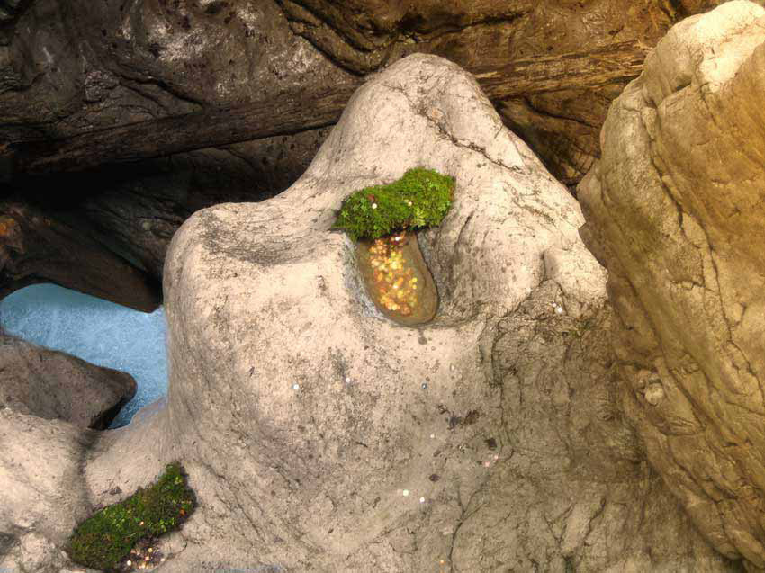 Bild einer Klamm, Münzen geworfen in die Klamm, gesammelt in einer mulde eines Steines 